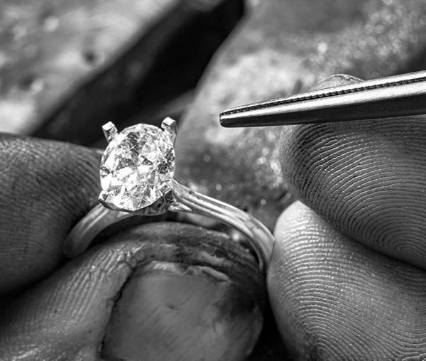 Mobile image of a jeweler setting an oval center diamond in an engagement ring